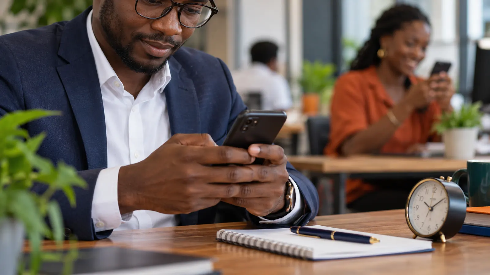 Un commercial relance un prospect depuis son téléphone, un réveil posé sur le bureau